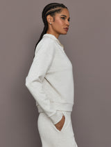 Model is wearing Interlock half zip pullover in Moonbeam Heather, side profile view.