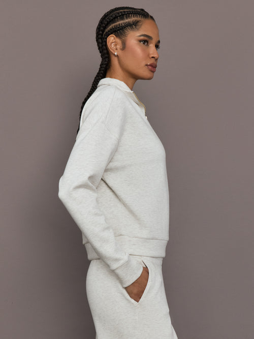 Model is wearing Interlock half zip pullover in Moonbeam Heather, side profile view.