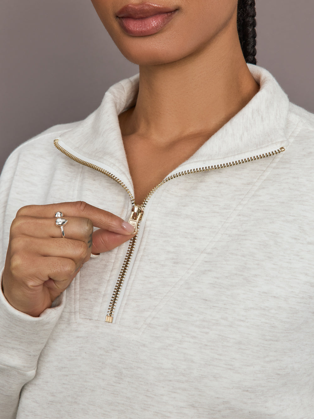 Model is wearing Interlock half zip pullover in Moonbeam Heather, close-up zipper detail.