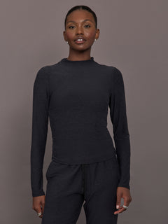 Model wears a mock neck long sleeve athletic top with extremely soft texture. 