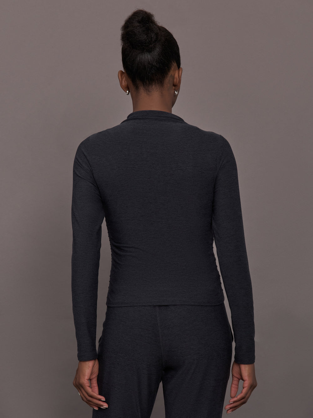 Model wears a mock neck long sleeve athletic top with extremely soft texture. 
