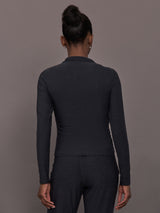 Model wears a mock neck long sleeve athletic top with extremely soft texture. 