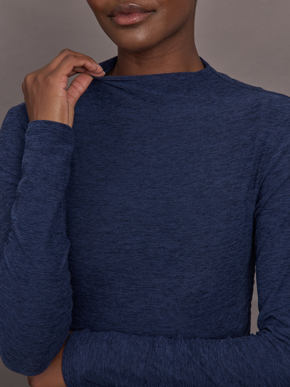 Model wears a long sleeve mock neck navy heather athletic wear top. 