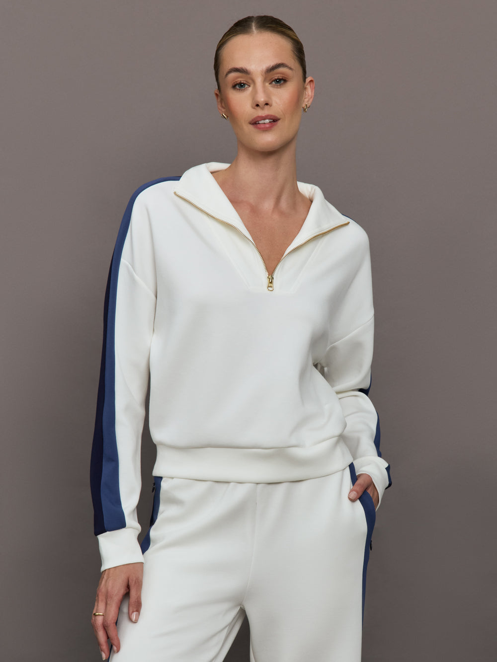 Model wearing an ivory half zip sweatshirt with blue accents.