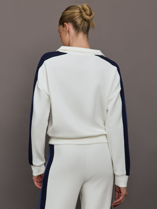 Model wearing an ivory half zip sweatshirt with blue accents.