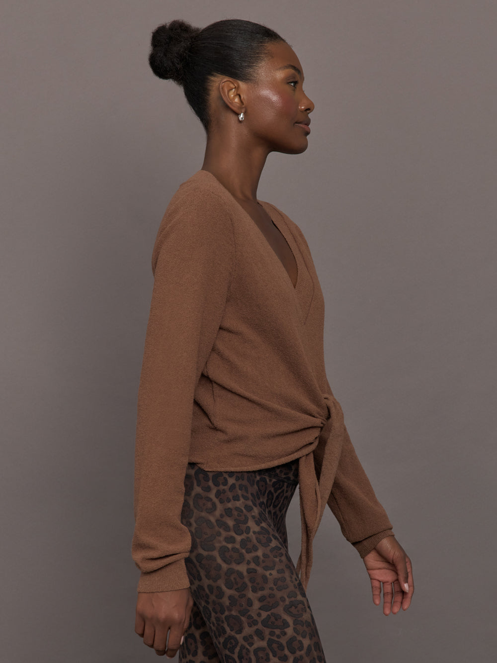 Model wearing a brown long-sleeve sweater with a knot detail 