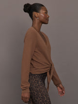 Model wearing a brown long-sleeve sweater with a knot detail 