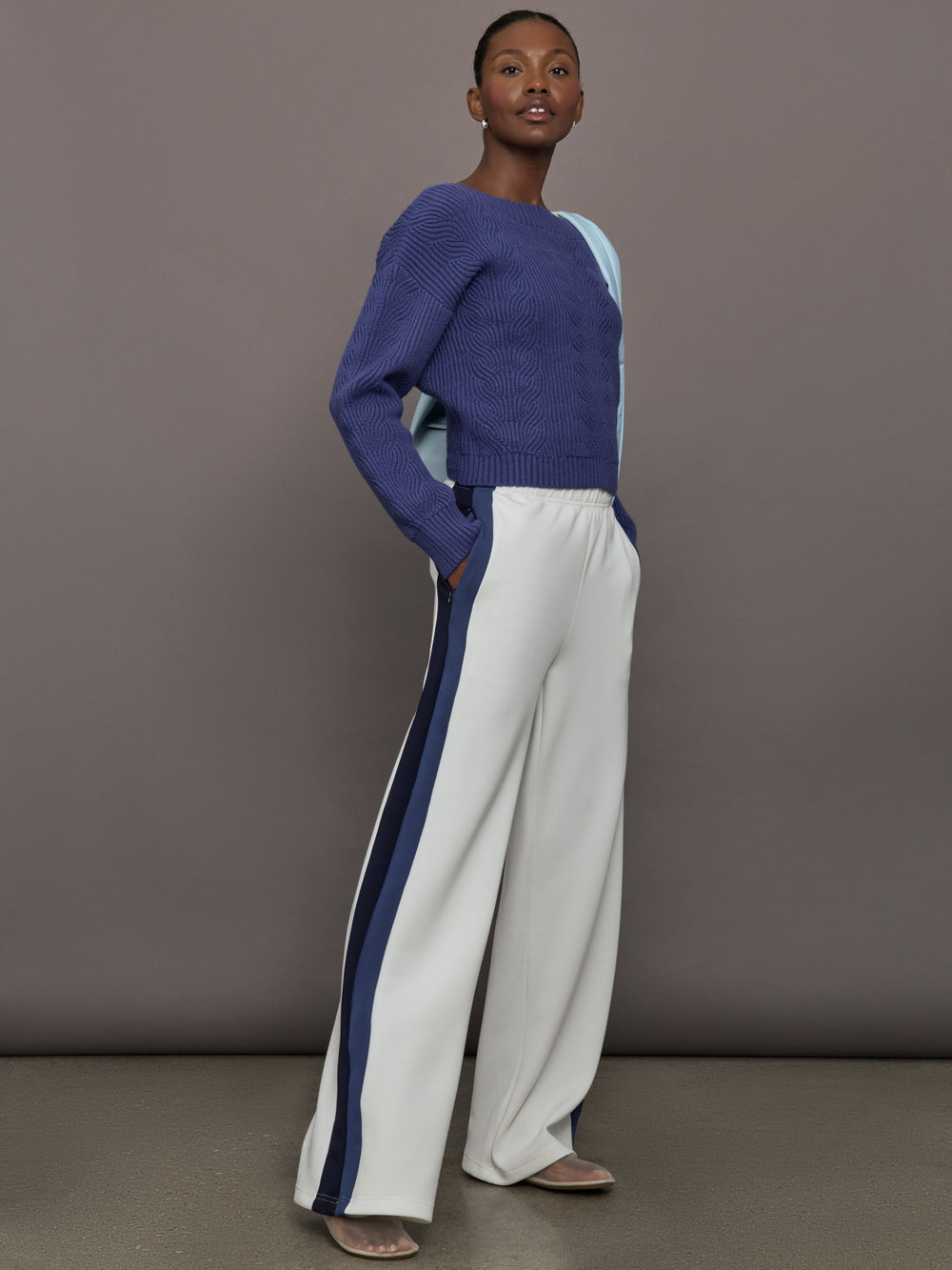 Model wearing blue sweater with a twist in the back.