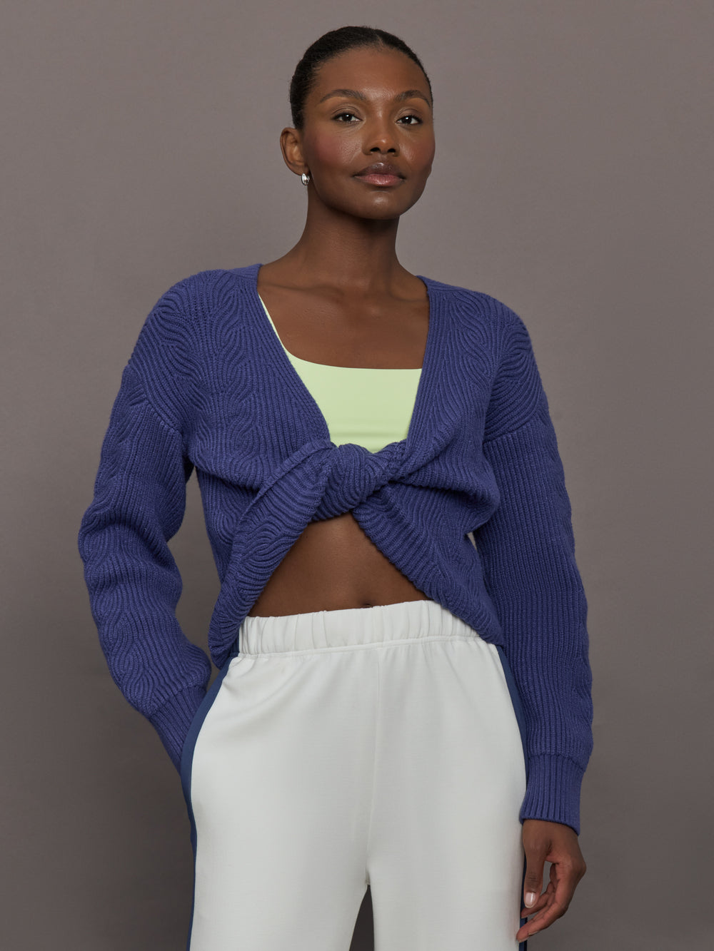 Model wearing blue sweater with a twist in the back.