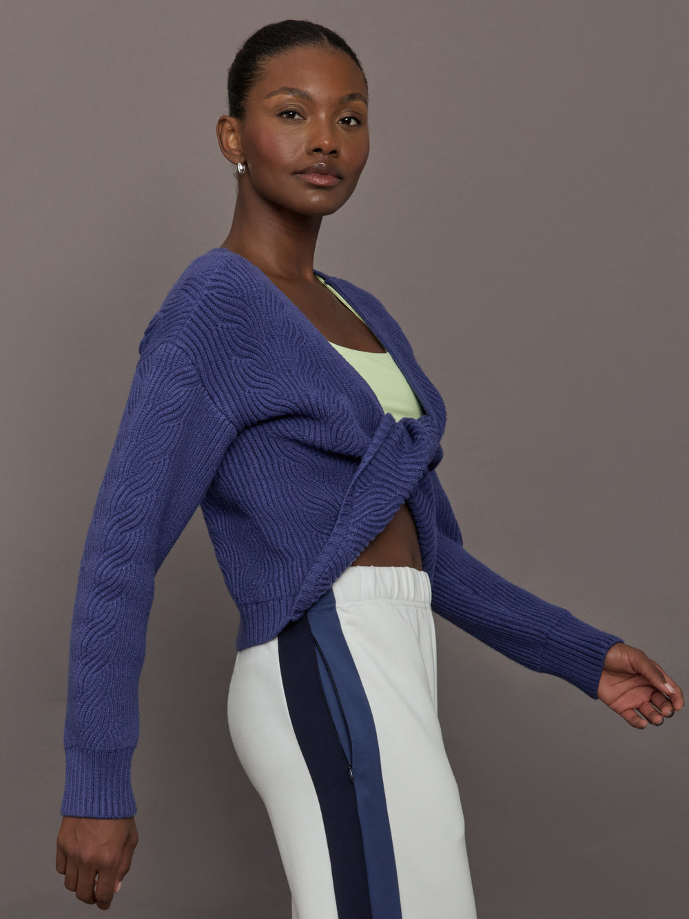 Model wearing blue sweater with a twist in the back.