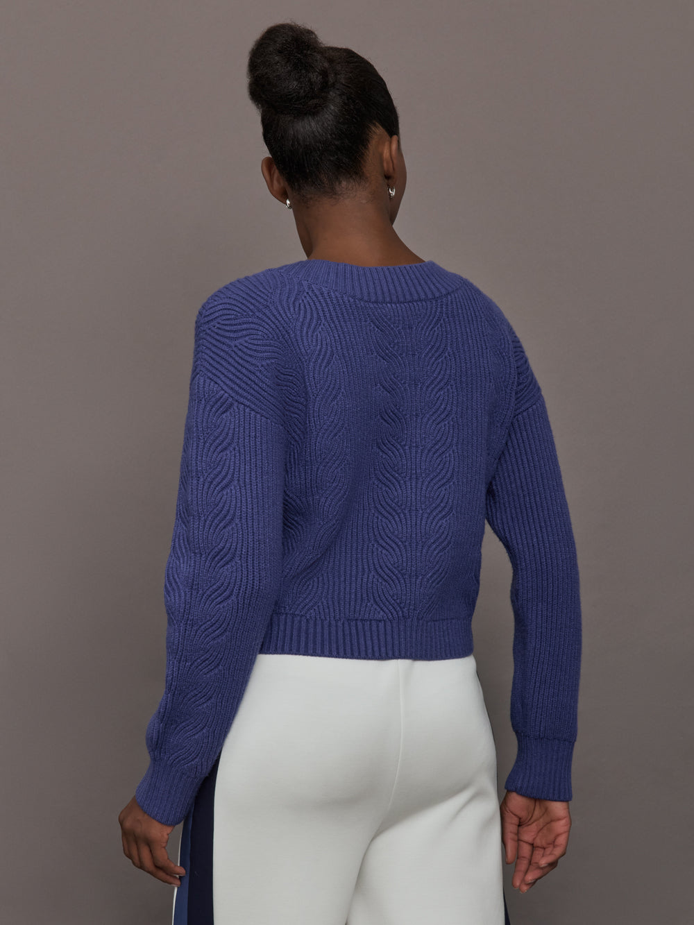 Model wearing blue sweater with a twist in the back.