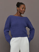 Model wearing blue sweater with a twist in the back.