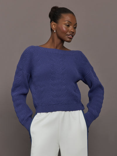 Model wearing blue sweater with a twist in the back.