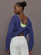 Model wearing blue sweater with a twist in the back.