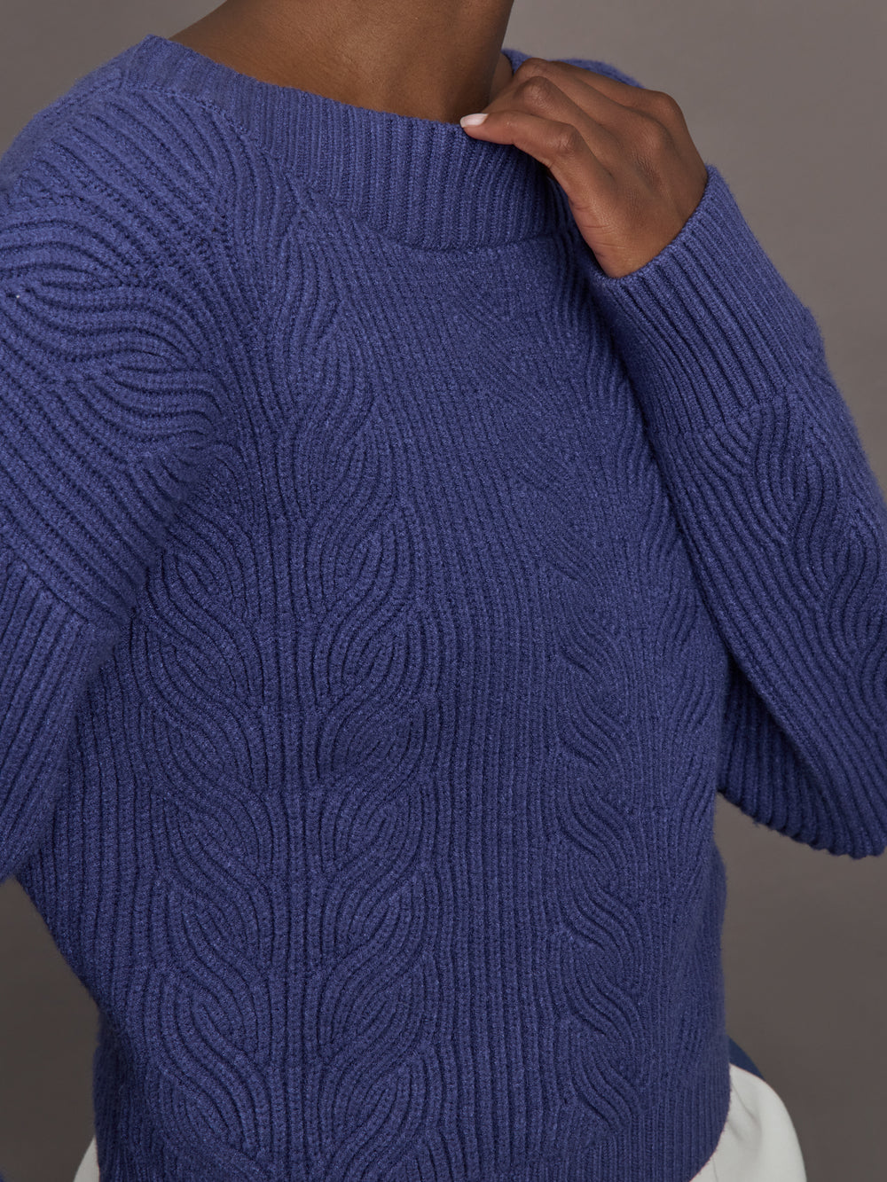 Model wearing blue sweater with a twist in the back.