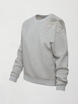 Product shot of grey bow embellished sweatshirt with jeweled bow accent on shoulder, front angled view.