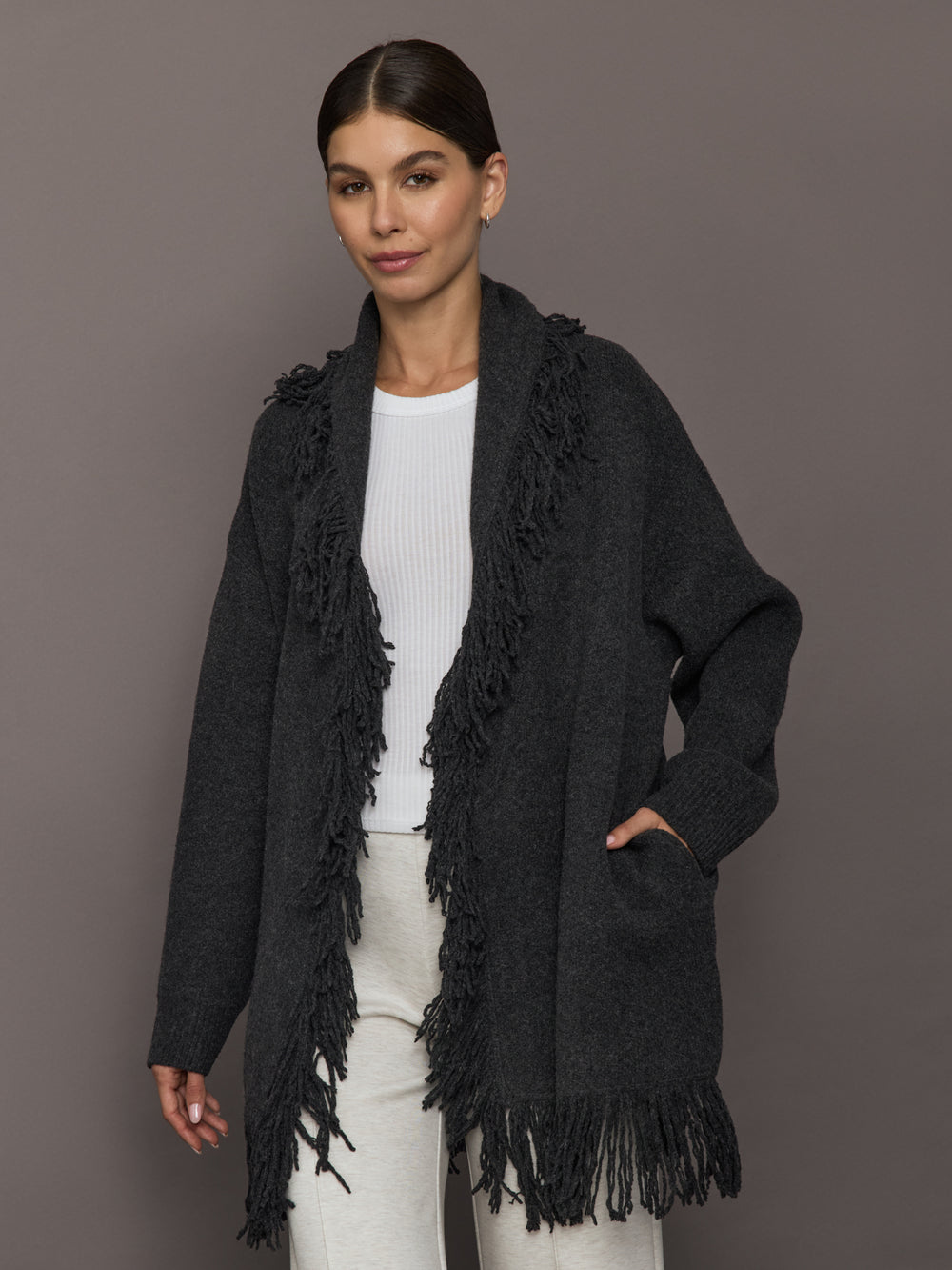 Model wearing Tassel Shawl Collar Sweater in charcoal with fringe trim, front view.