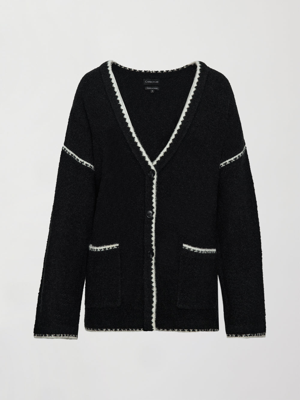 Flat lay of Sweater with Scarf in black with cream whipstitch trim and attached fringe scarf, front view.