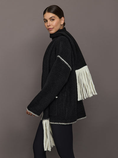 Side view of Sweater with Scarf in black with cream contrast whipstitch and long fringe scarf detail.