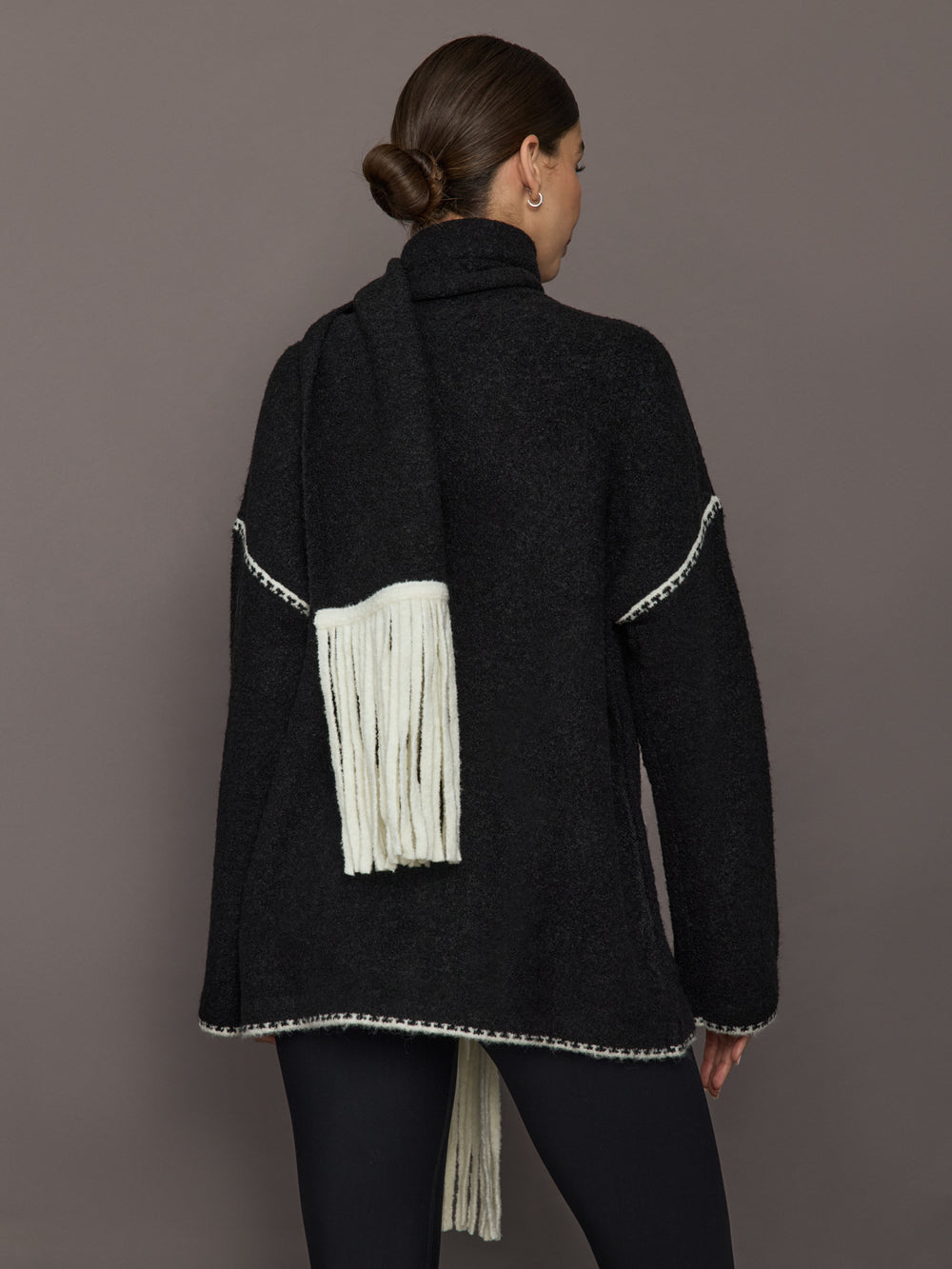 Back view of Sweater with Scarf in black showing cream whipstitch trim and scarf draped with fringe.