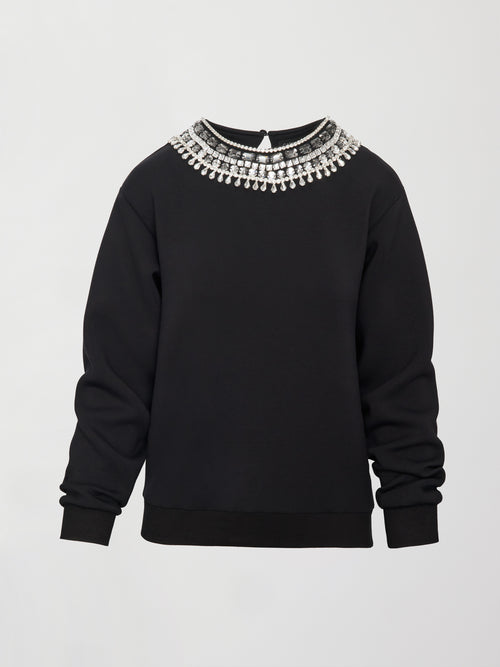 Flat lay of black jewel embellished sweatshirt with crystal neckline detail on white background.