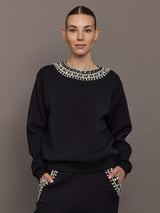 Model wearing black jewel embellished sweatshirt with crystal neckline detail, front view.