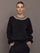 Model wearing black jewel embellished sweatshirt with crystal neckline detail, front view.