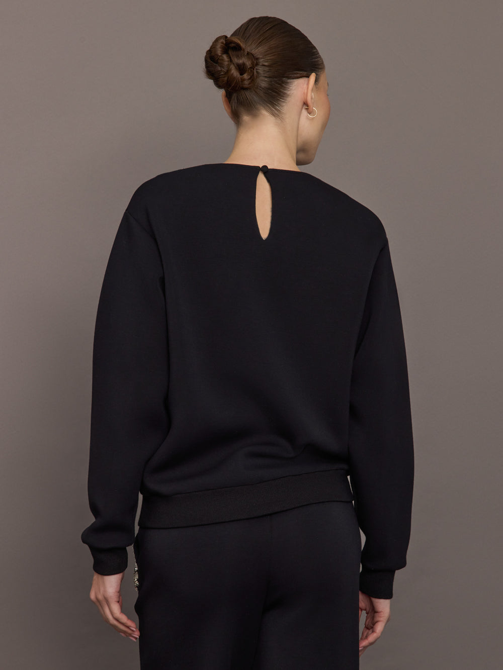 Back view of black jewel embellished sweatshirt with keyhole closure at neck.