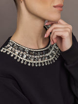 Close-up of black sweatshirt neckline with silver jewel and crystal embellishments.