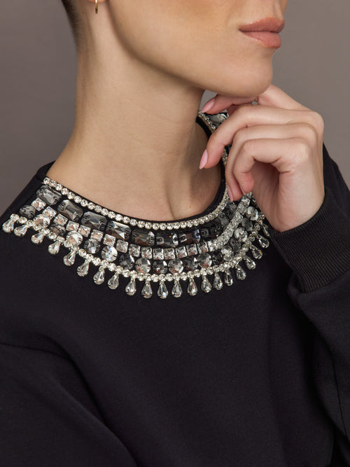 Close-up of black sweatshirt neckline with silver jewel and crystal embellishments.