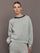 Model wearing grey jewel embellished sweatshirt with crystal neckline, front view.