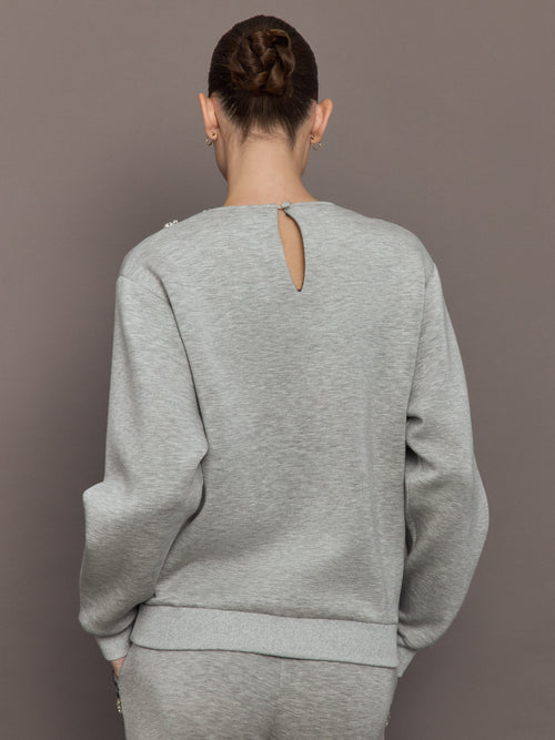 Back view of grey jewel embellished sweatshirt with keyhole button closure.