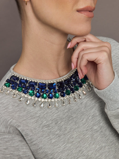 Close-up of jewel embellished sweatshirt showing crystal and gem neckline detail.