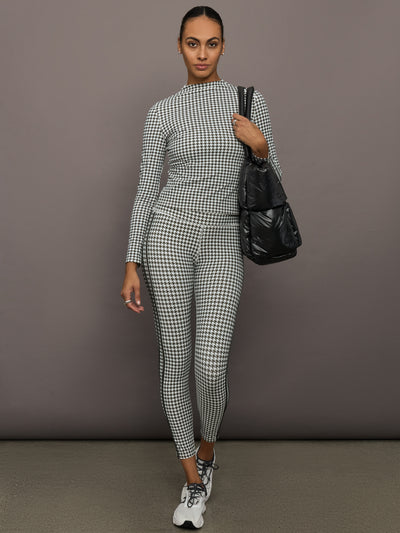 Full outfit view of houndstooth mock neck top with matching leggings, styled with sneakers and black tote.