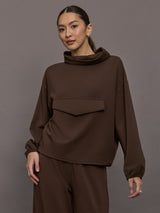 Model is wearing Scuba Funnel Neck Pullover in Carafe, front view.