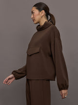 Model is wearing Scuba Funnel Neck Pullover in Carafe, side profile view.