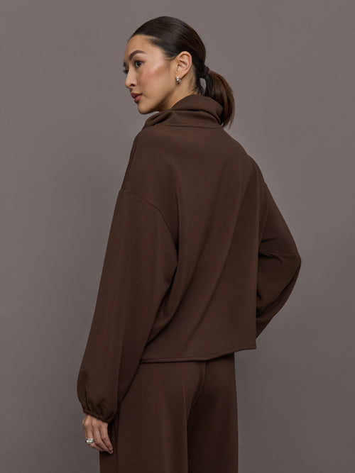 Model is wearing Scuba Funnel Neck Pullover in Carafe, back view.