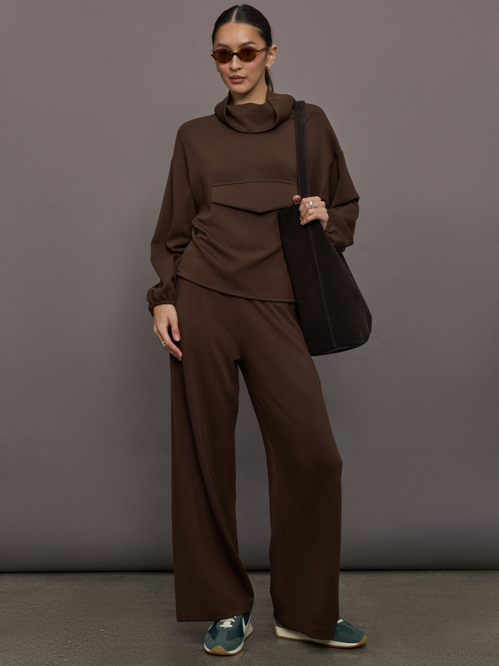 Model is wearing Scuba Funnel Neck Pullover in Carafe, full body styled with tote and sunglasses.
