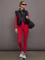 Model wears a long sleeve, deep v neck top in bright red with an overlapping seam at the bottom creating the effect of a wrap top. 