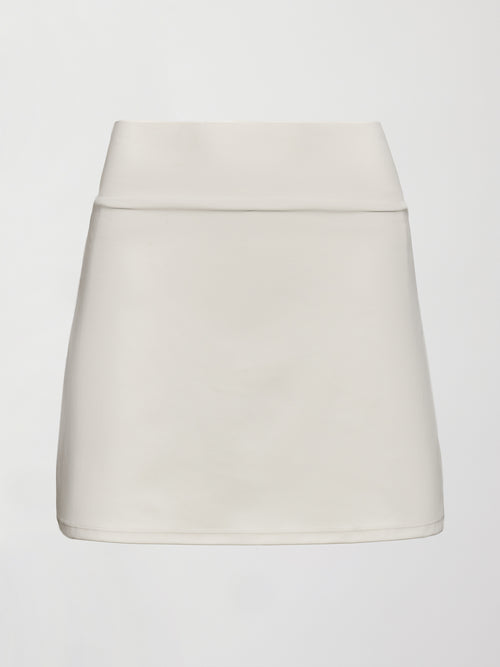 Model wears white tennis skirt with a smooth, fitted waistband and subtle flare.
