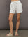 Model wears ivory Interlock Curved Hem Shorts with a smooth finish, featuring a curved hemline