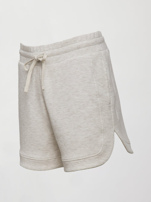 Model wears ivory Interlock Curved Hem Shorts with a smooth finish, featuring a curved hemline