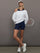 Model wearing navy biker short styled with oversized white sweatshirt and cap, full body view.