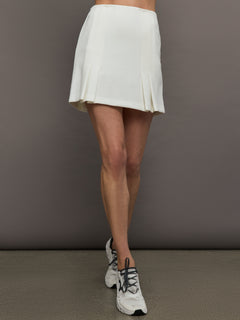 Model wears a white pleated miniskirt. 