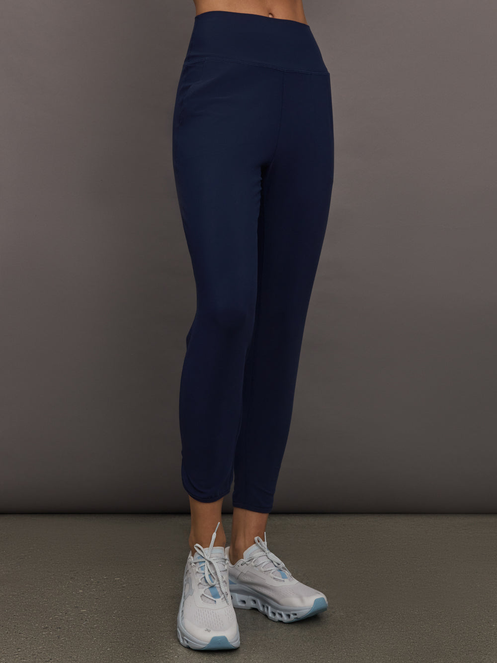 Model wears navy high-rise joggers with a slim, relaxed fit and a slightly cropped tulip-shaped hem and a wide waistband.
