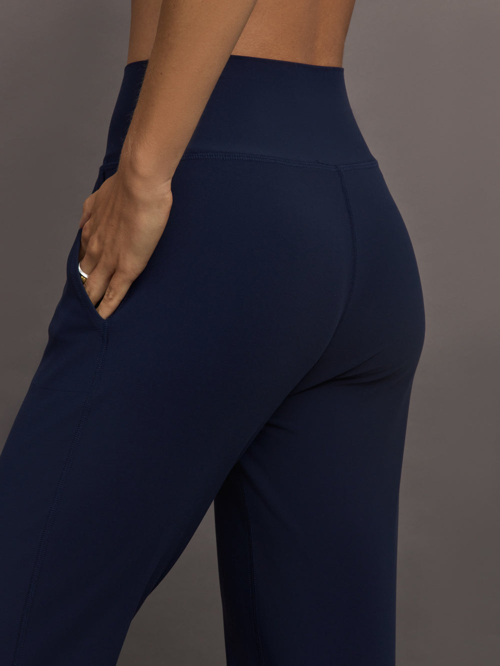 Model wears navy high-rise joggers with a slim, relaxed fit and a slightly cropped tulip-shaped hem and a wide waistband.
