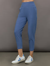 Model wears a pair of lightweight blue joggers with a wide waistband and pockets. 