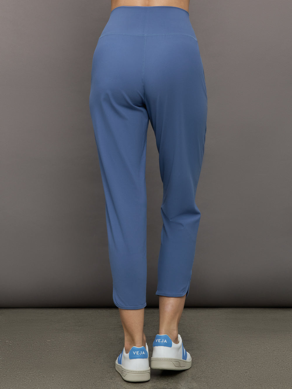 Model wears a pair of lightweight blue joggers with a wide waistband and pockets. 