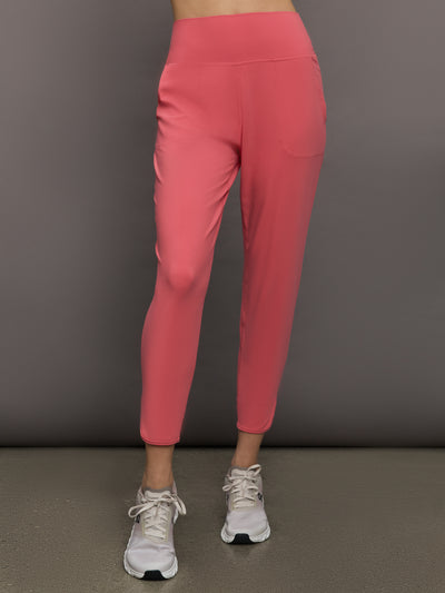 Model wears a buttery soft, high waisted, salmon pink colored pair of jogger sweatpants. 