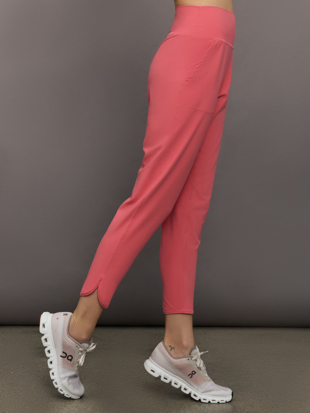 Model wears a buttery soft, high waisted, salmon pink colored pair of jogger sweatpants. 